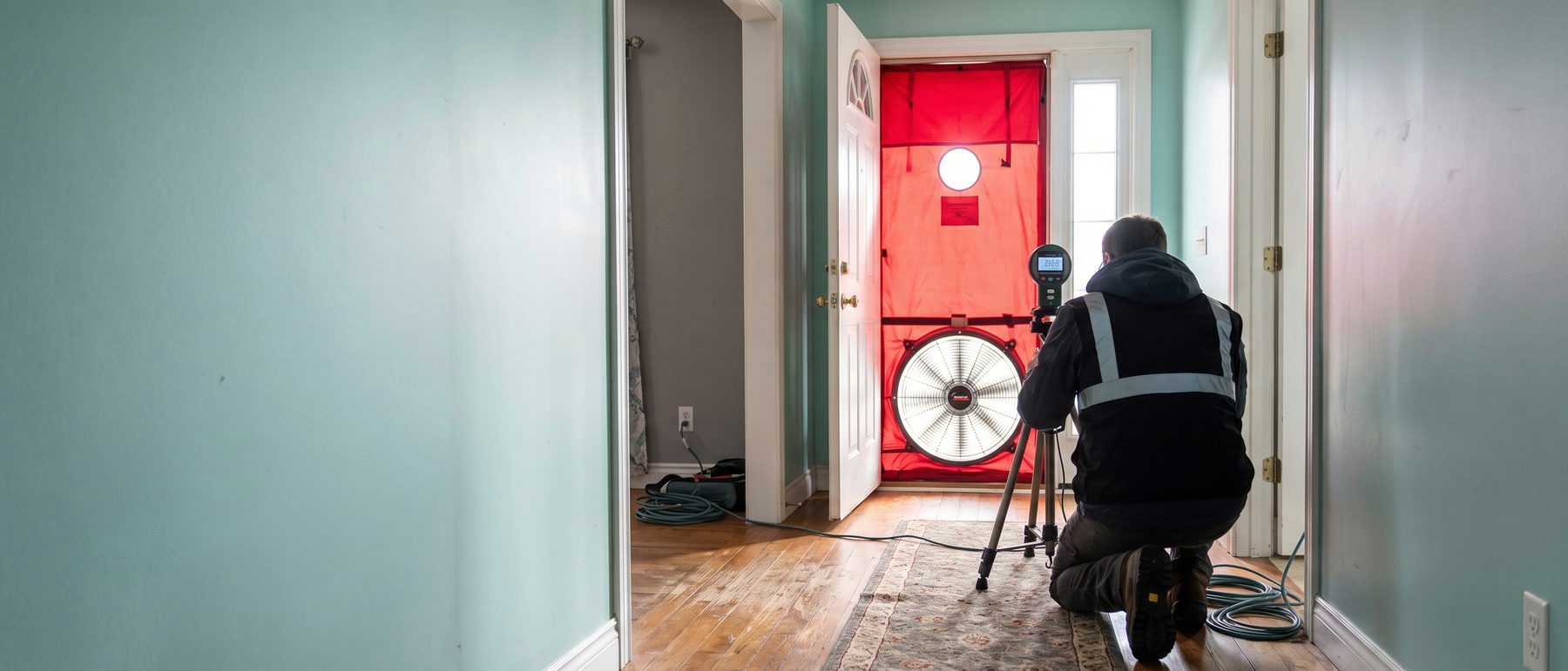 Home energy auditor setting up a blower door fan in a front doorway